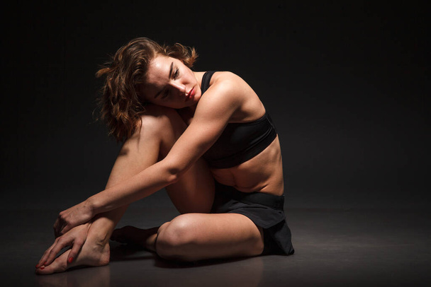 Young girl doing yoga on a black background - Фото, зображення