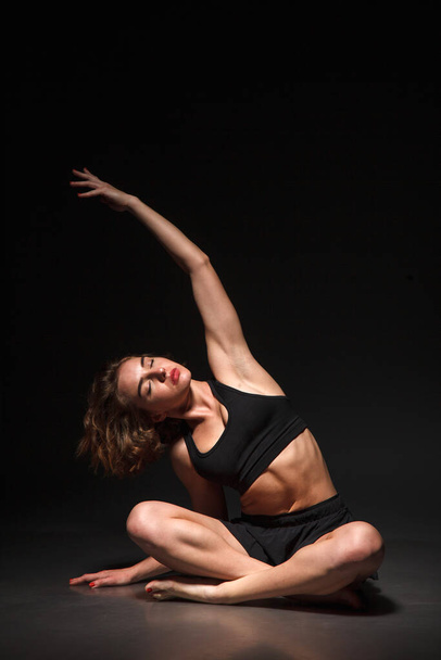 Young girl doing yoga on a black background - Fotoğraf, Görsel
