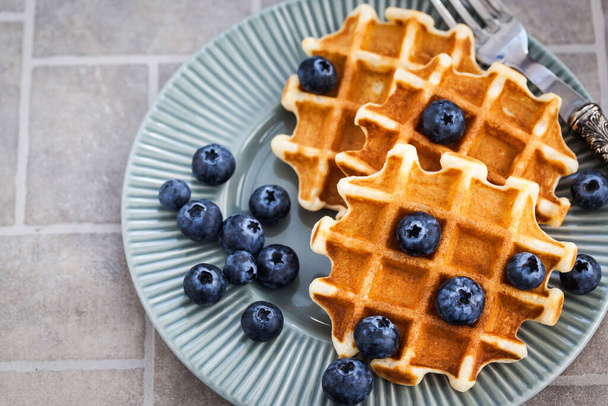 Homemade belgian waffles with fresh blueberries, close up - Fotó, kép