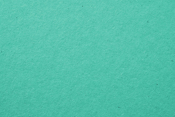 The surface of turquoise cardboard. Rough paper texture with cellulose fibers. Saturated aquamarine. Background or wallpaper. Top view from above. Macro - 写真・画像