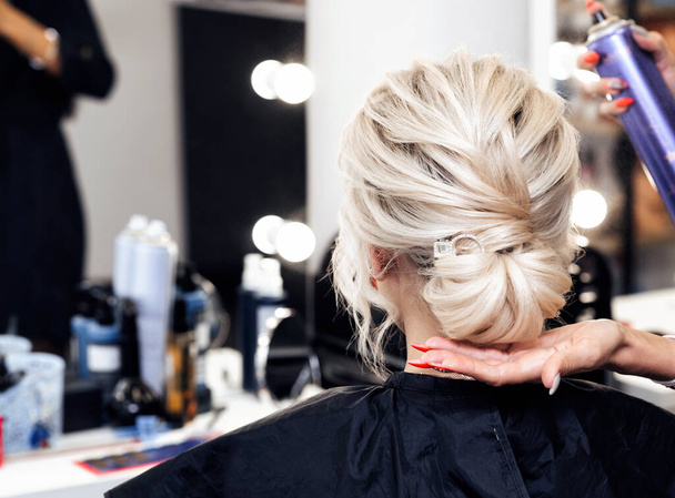 coiffeur fait sa propre coiffure mains un chignon sur la tête d'une fille blonde - Photo, image