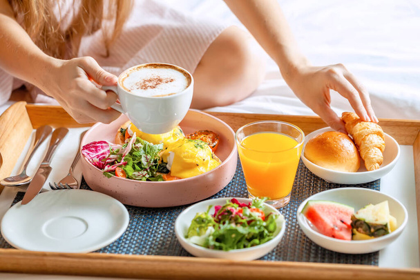 Breakfast in Bed with Coffee, Orange Juice, Salad, Fruits and Eggs Benedict - 写真・画像