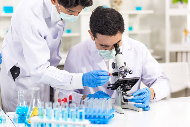 Biológia-tudományi laboratóriumokban dolgozó egészségügyi kutatók. Két fiatal kutató együtt dolgozik a vírus laboratóriumi elemzésén.. - Fotó, kép