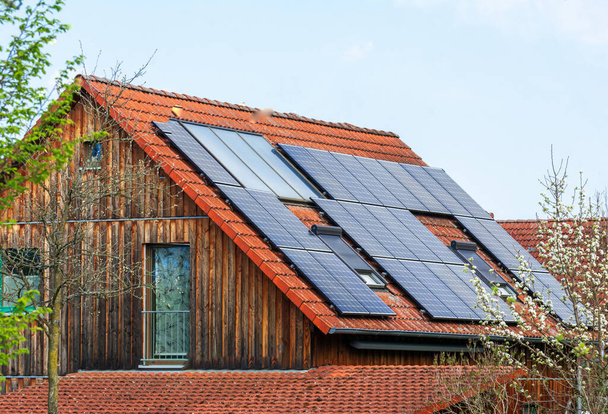 Alternatif enerji üretimi için çatıda fotovoltaik güneş pilleri olan genel modern ev - Fotoğraf, Görsel