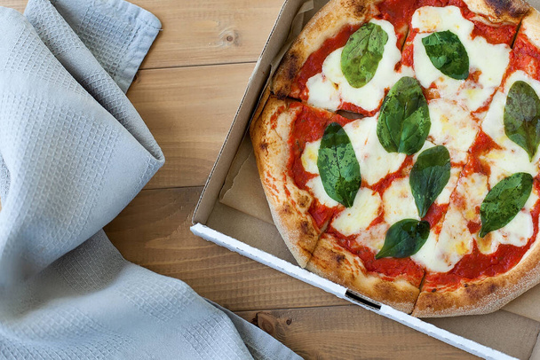 Top view Bardzo gorąca włoska pizza na białym drewnianym stole z grzybami, bazylią, pomidorami, oliwkami i serem. Wyglądaj jak - Zdjęcie, obraz
