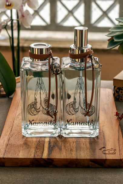 Aromático purificador de ar em uma garrafa de vidro transparente com símbolo namaste no rótulo
 - Foto, Imagem