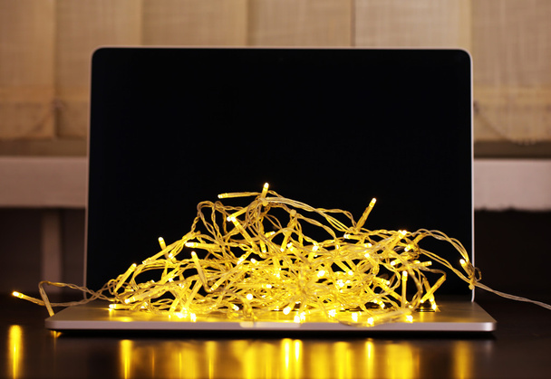Laptop with garland, on office interior background - Foto, Imagen