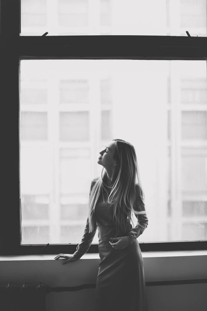 Young woman portait indoors. Silhouette of a girl in front of a window. black and white photography, monochrome, photo noir - 写真・画像