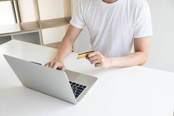 Szoros kéz egy férfi tartja a hitelkártyát, és használja a számítógép notebook az online vásárlás.   - Fotó, kép