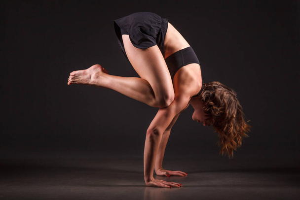 Young girl doing yoga on a black background - Fotó, kép