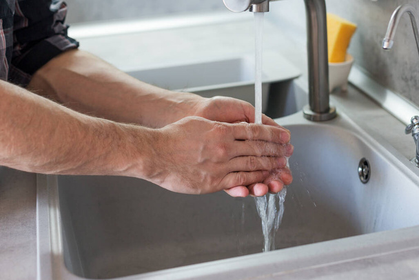 a man washes his hands in the kitchen sink. Modern kitchen - 写真・画像