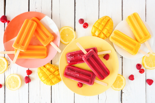 Summer table scene with colorful fruit popsicles. Above view on a white wood background. - Foto, afbeelding