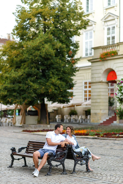 Молода закохана пара сидить на лавці. Хлопець і дівчина дивляться один одному в очі. Перше побачення
. - Фото, зображення