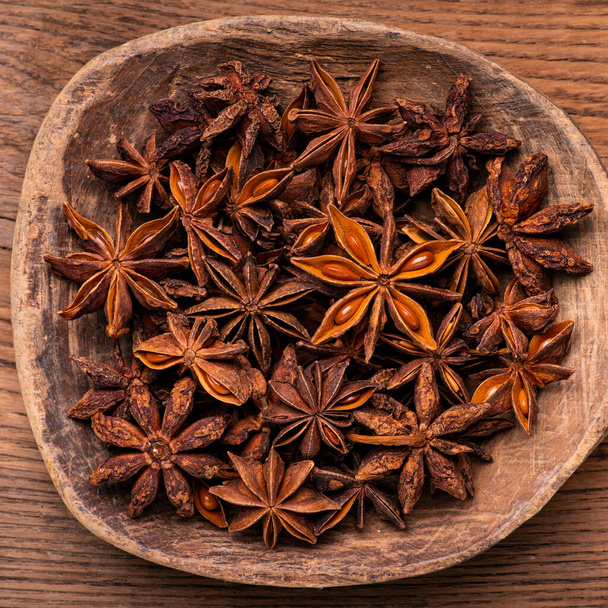 in the foreground, with a top view, a pile of star anise in the old wooden bowl - Photo, Image