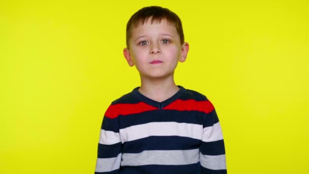 Ernstes kleines Kind, das in die Kamera blickt und auf gelbem Hintergrund lächelt - Filmmaterial, Video