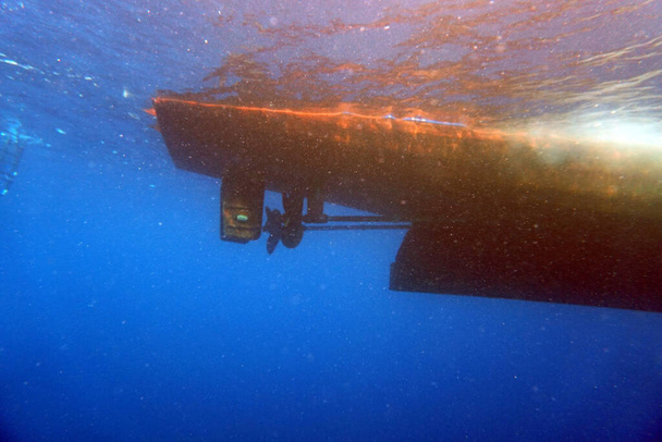 дно пірнаючого човна з гвинтом під водою на синьому фоні
 - Фото, зображення