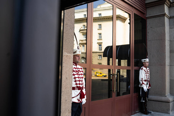 SOFIA BULGARIA August 12, 2019 Guards of Honor dressed in 19th century red and white parade uniforms in front of the Presidency of Bulgarian building republic. The main entrance of Presidency. - Foto, Bild