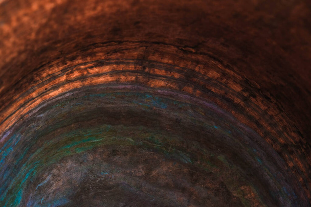 Koperen oppervlak van de binnenwand van een oude koperen ketel. De bodem van de pot in gekleurde kringen van oxidatie van koper. Rustig aan. Kopieerruimte. - Foto, afbeelding
