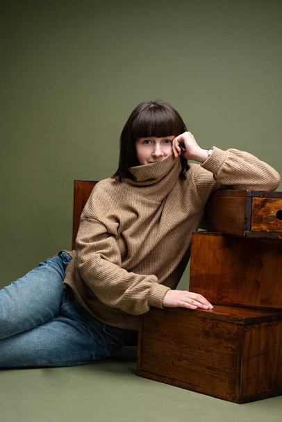 a girl sits on the floor in a photo studio, put her elbow on boxes, thinks - Fotó, kép
