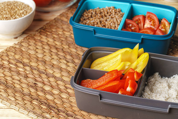 Two lunch boxes with cooked groats and cut vegetables - Photo, image