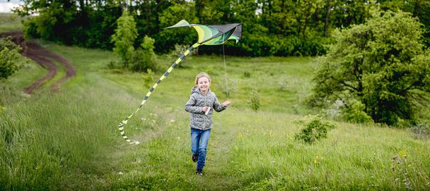 Happy little girl flying bright kite - Valokuva, kuva