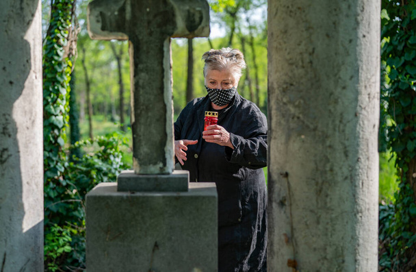 Mujer mayor enmascarada en un cementerio
 - Foto, Imagen