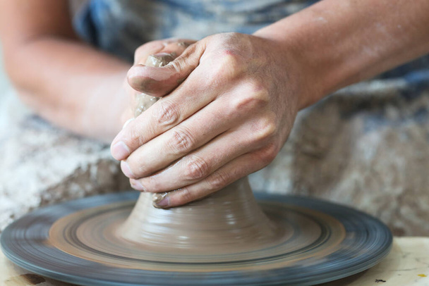 Руки горшечника делают из глины на гончарном круге. Поттер делает на гончарном круге глиняный горшок. - Фото, изображение