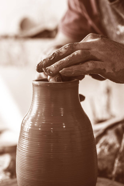 Pottenbakkershanden maken in klei op aardewerk wiel. Pottenbakker maakt op het aardewerk wiel klei pot. - Foto, afbeelding