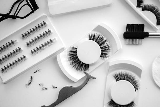 Fake Eyelashes & Accessories. Composition with false eyelashes on table.Flat composition with false eyelashes, cosmetic products and tools on  white background. - Photo, Image