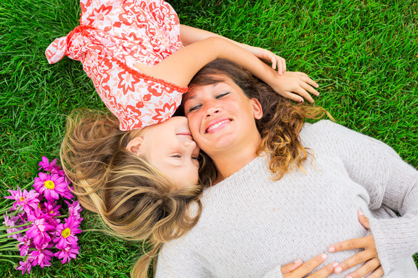 Mother and daughter lying together outside on grass - Foto, immagini