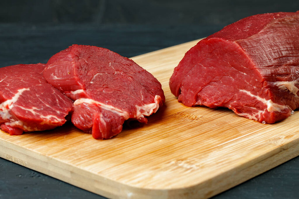 Slice of raw beef fillet on wooden board - Фото, изображение