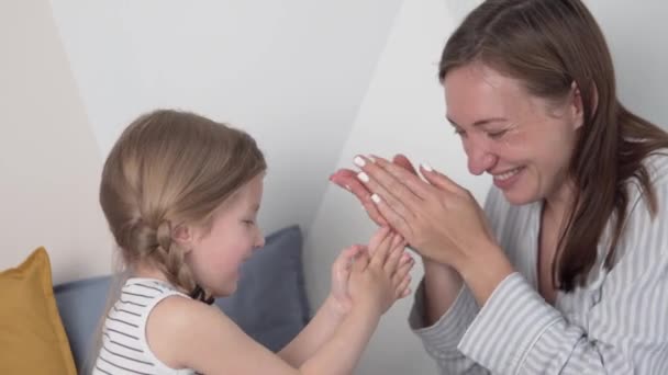 Mãe e pequena filha alegremente aplicar creme no corpo e rosto
 - Filmagem, Vídeo
