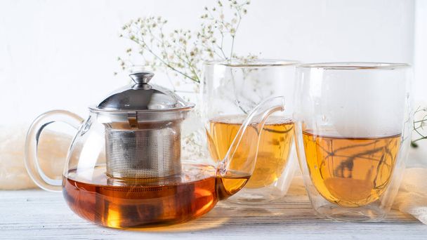 Romantische thee voor koppels. Zwarte thee in gewone glazen theepot. Warme thee in dubbele wandbekers. Dubbelwandige mokken. - Foto, afbeelding