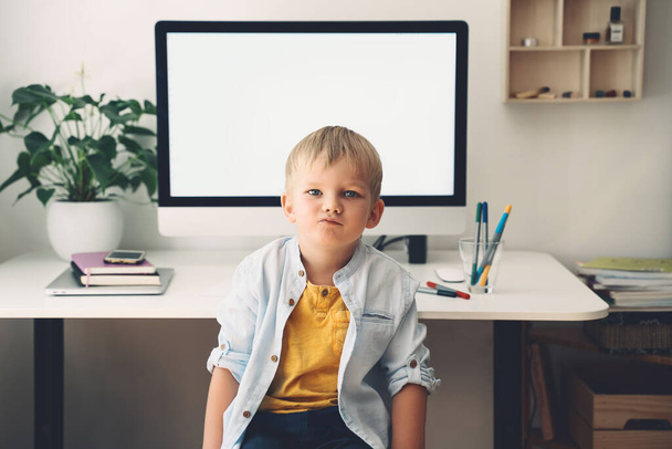 Portrait of preschool child boy on background of computer with blank white screen in home interior. Children online learning, distance education, development or entertainment. Kids homeschooling. - Foto, Imagem
