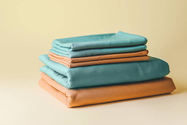 Stapel sauberer Bettwäsche auf farbigem Hintergrund - Foto, Bild