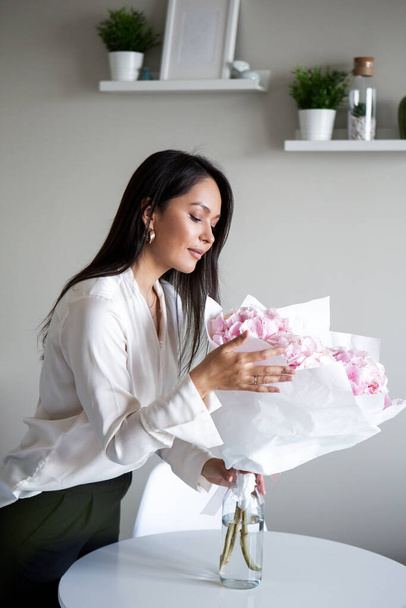 Young woman holds light tender pink hydrangea bouquet, closeup photo in home interior - Foto, Imagem