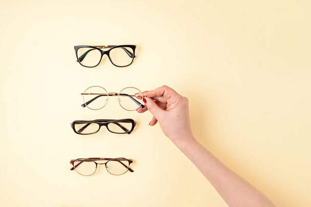 Gözlük tutan kadın. Optik mağaza, gözlük seçimi, göz testi, göz doktorunda vizyon muayenesi moda aksesuarları konsepti. Üst manzara, düz uzanma - Fotoğraf, Görsel
