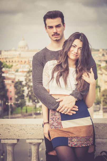 Urlaub in Rom. Schöne schöne junge italienische Paar umarmen sich im Freien. Ein Paar, ein junger Mann und eine Frau, umarmen sich auf einer Terrasse im historischen Zentrum von Rom, Italien. - Foto, Bild