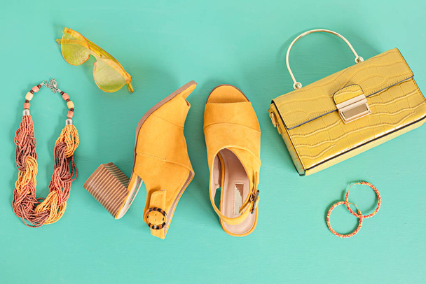 Flat lay with woman fashion accessories in yellow color over turquoise background. Fashion, online beauty blog, summer style, shopping and trends concept - Photo, Image