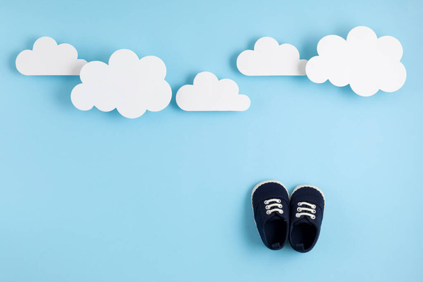 Lindos zapatos de niño recién nacido con decoración festiva sobre fondo azul. Ducha para bebés, cumpleaños, invitación o idea de tarjeta de felicitación
 - Foto, imagen