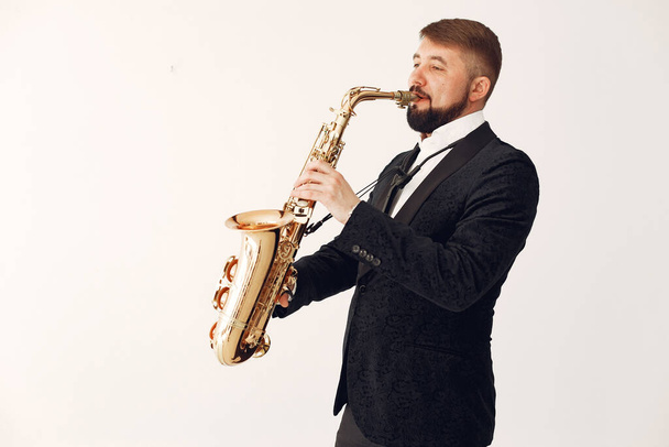 Man in black suit standing with a saxophone - Foto, afbeelding