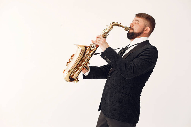 Man in black suit standing with a saxophone - Foto, Bild