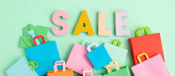Word Sale and shopping paper bags. Sesonal sale, online deals, discounts, promotion, shopping addiction concept - Photo, Image