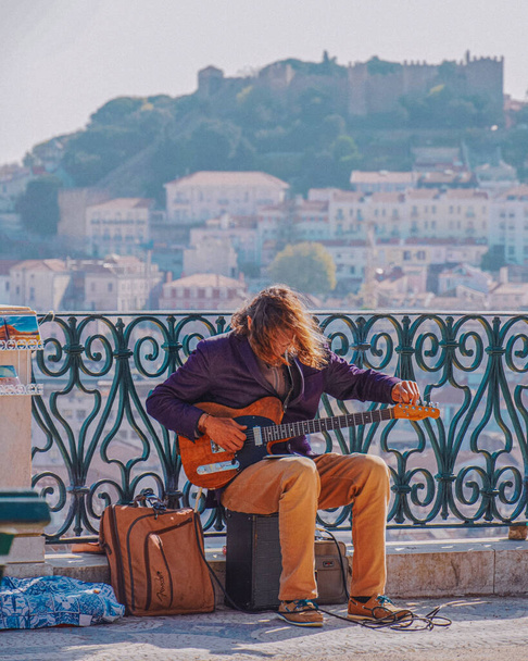 Undefined street musician trying to tune an electric guitar. Lisbon, Portugal. Playing in the street to make a living. Windy spring day. - Foto, immagini