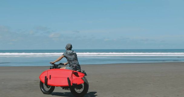 オートバイ愛好家がビーチでバイクを運転 - 写真・画像