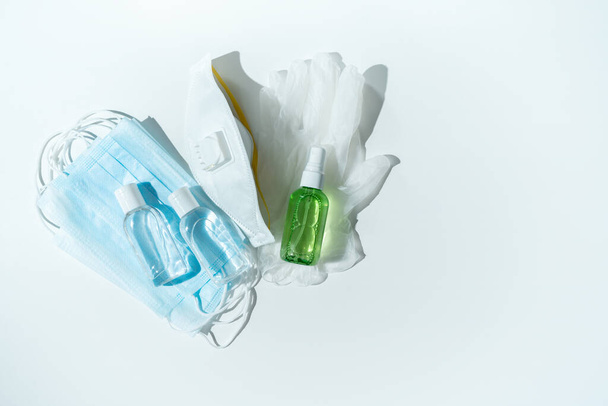Set of protecting disposable filtering safety face masks, gloves, sanitizer for hands on white background. Personal hygiene product. Pharmaceutical, medical background.  - Φωτογραφία, εικόνα