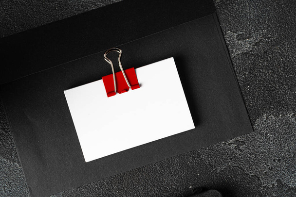 White businesscards united with a paper clip on a black rough background - Fotó, kép