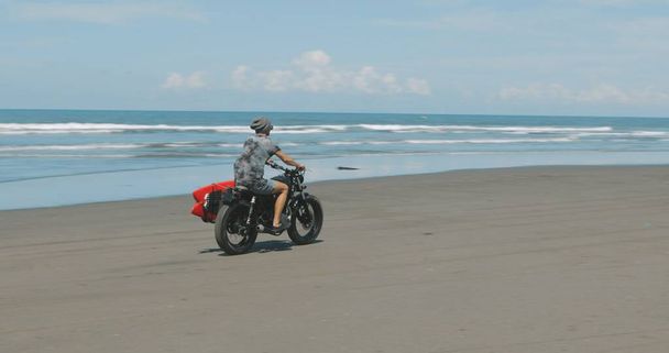 Motorcyclist driving his motorbike on the beach - Foto, imagen