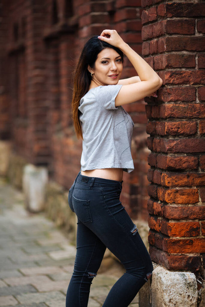 beautiful girl near the wall in jeans - Φωτογραφία, εικόνα