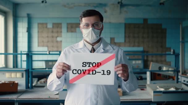A medical worker in protective glasses holds a sign saying Stop virus COVID-19 in his hands. - Séquence, vidéo